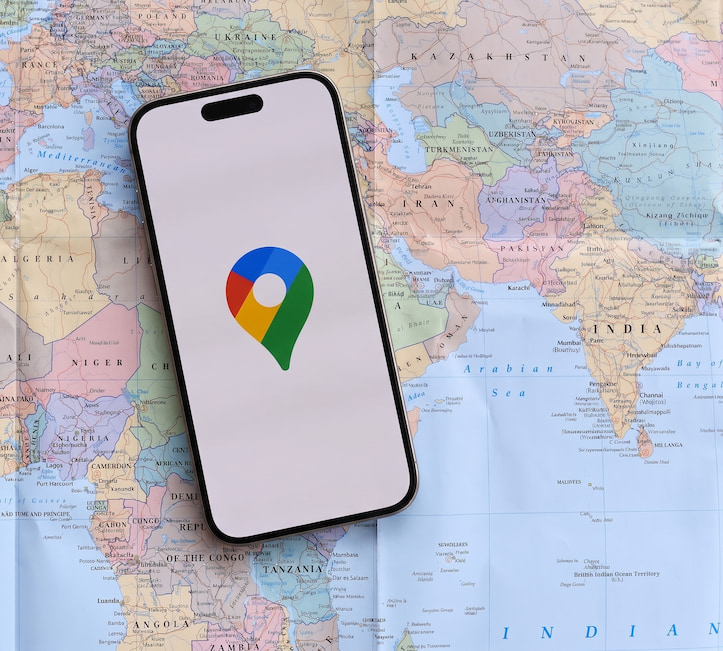 Smartphone displaying Google Maps app resting on a world map for local SEO optimization.